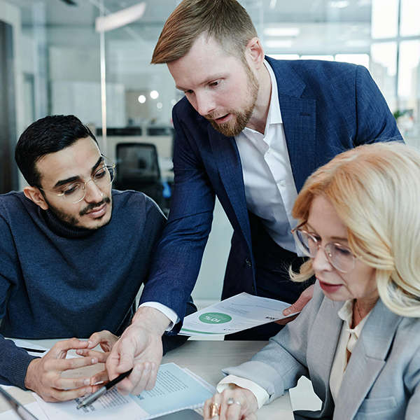 Three staffing agency recruiters reviewing resumes together and discussing candidates on a laptop